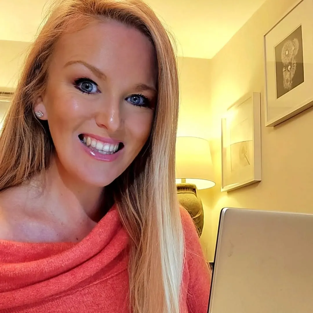 Steff smiling beside a laptop while working from home.